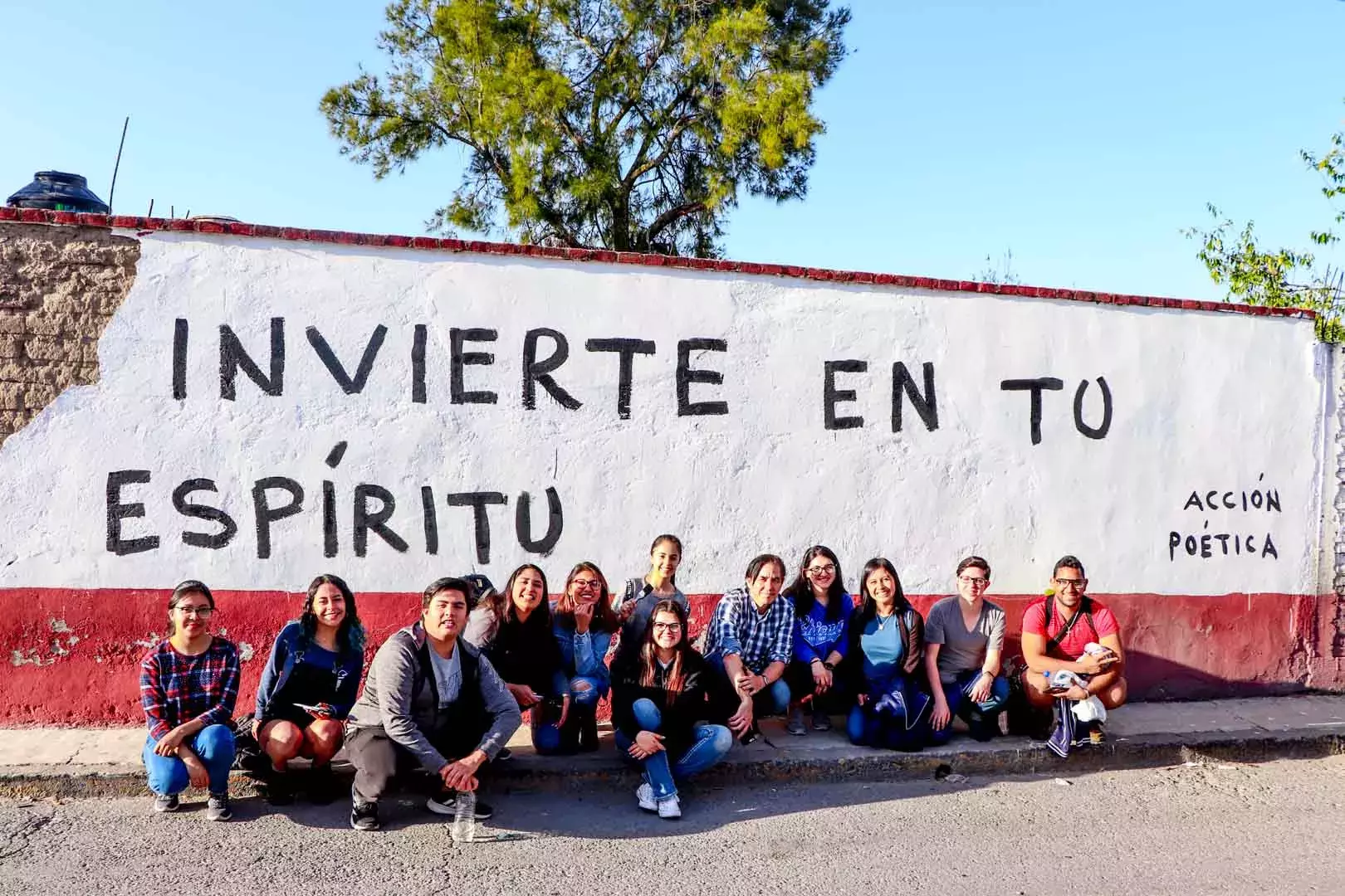 Alumnos y Armando Alanís pintando paredes con frases poéticas