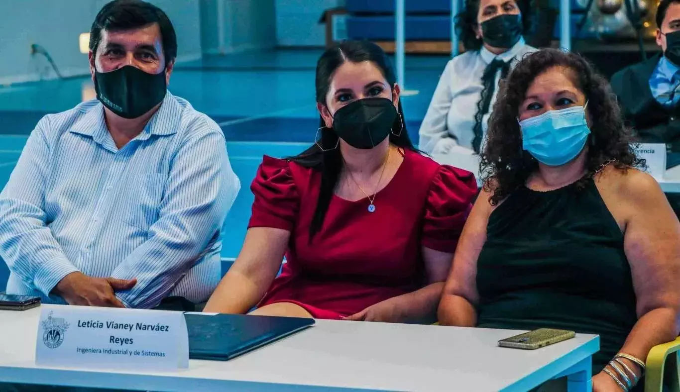 Padres de familia apoyando a su hija en su firma de título profesional.