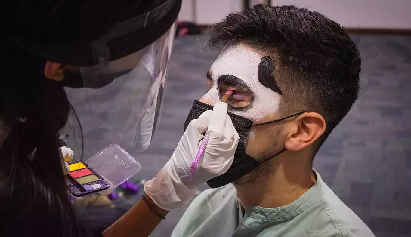 Un alumno está siendo maquillado por su comunidad