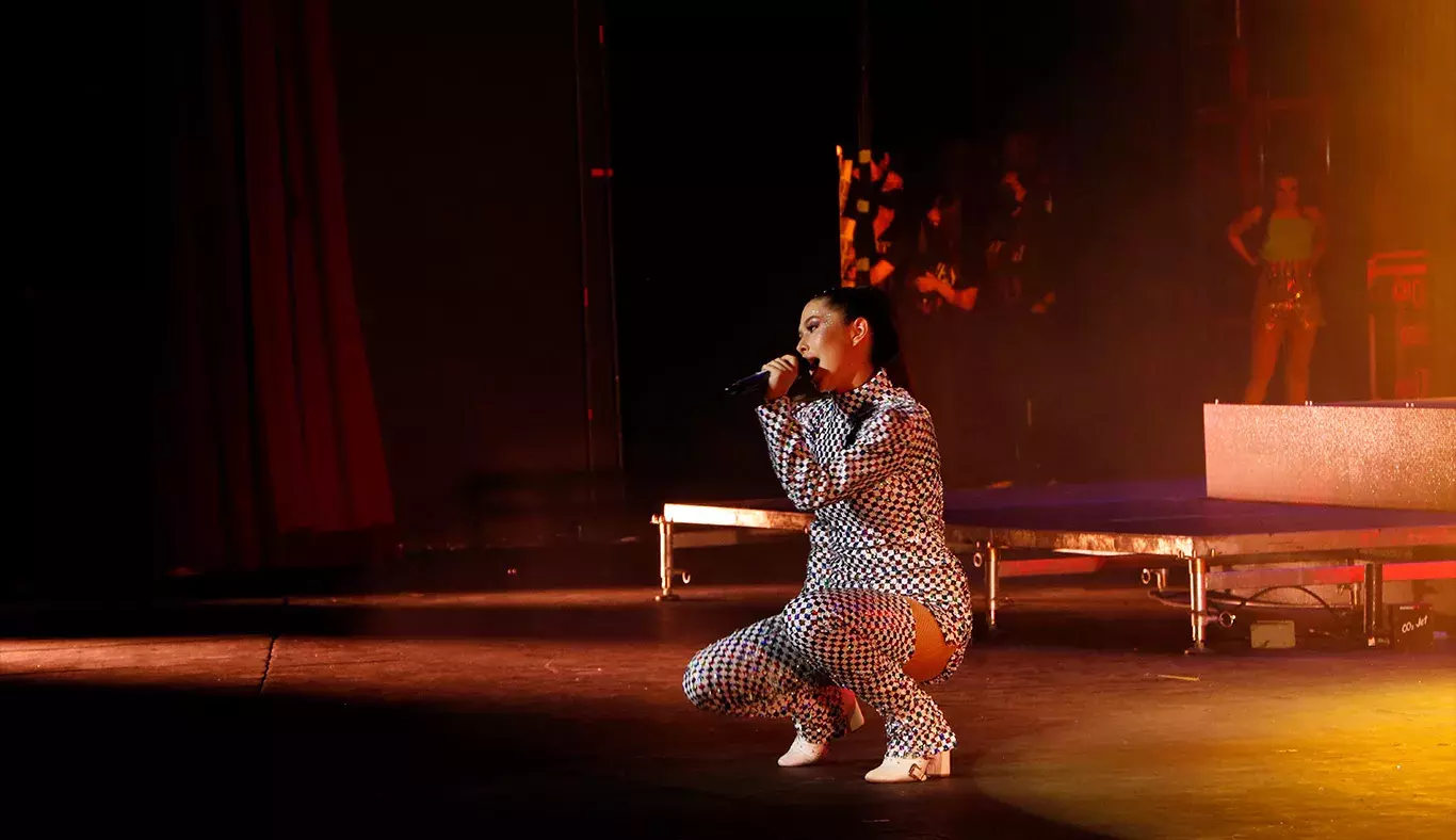 Cantante hincada cantando en el escenario