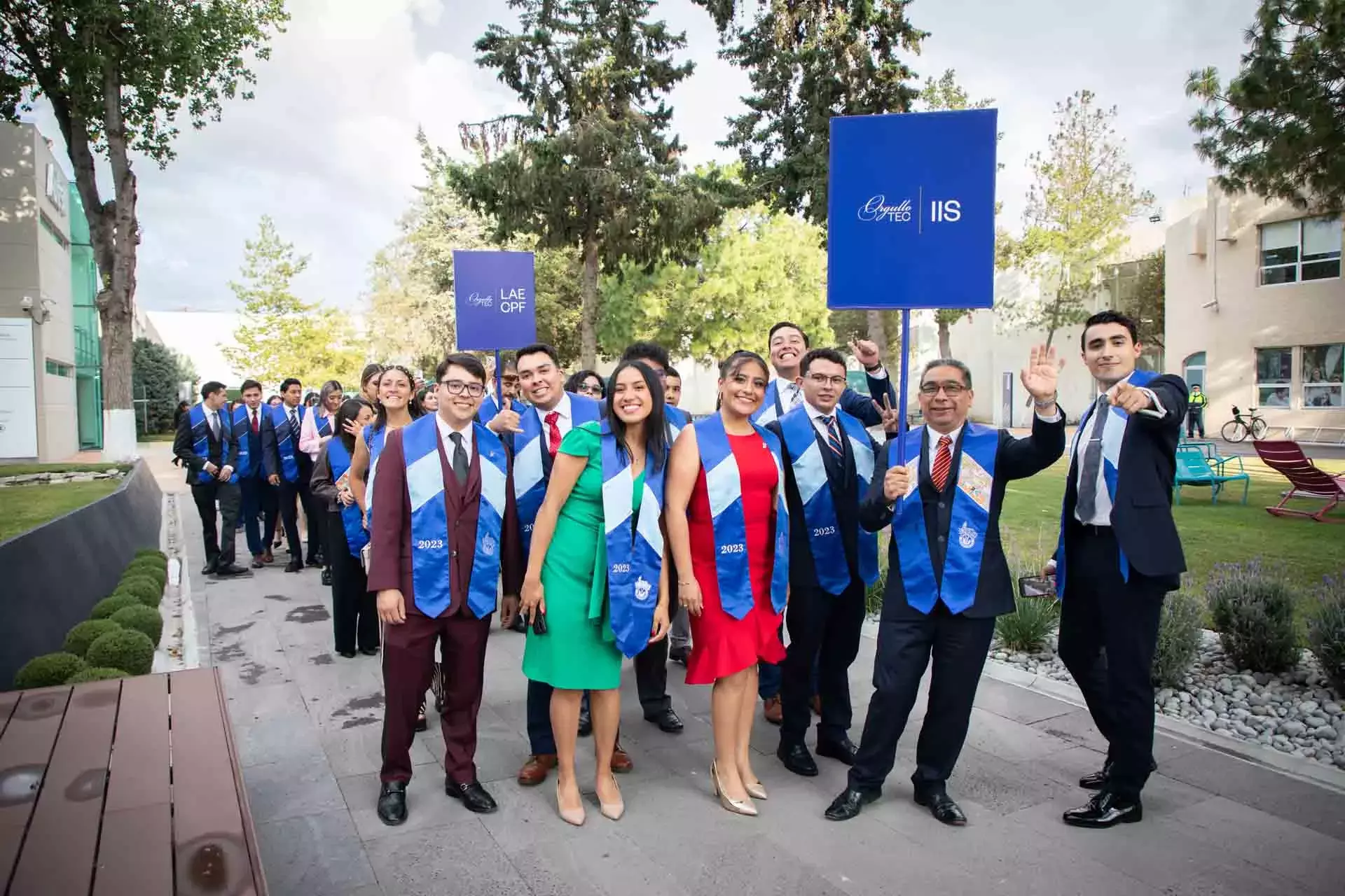 Graduados y graduadas posando al iare libre con profesores