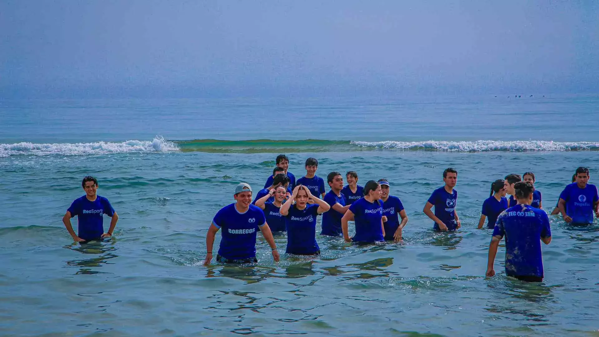 alumnos refrescándose en la orilla de la playa