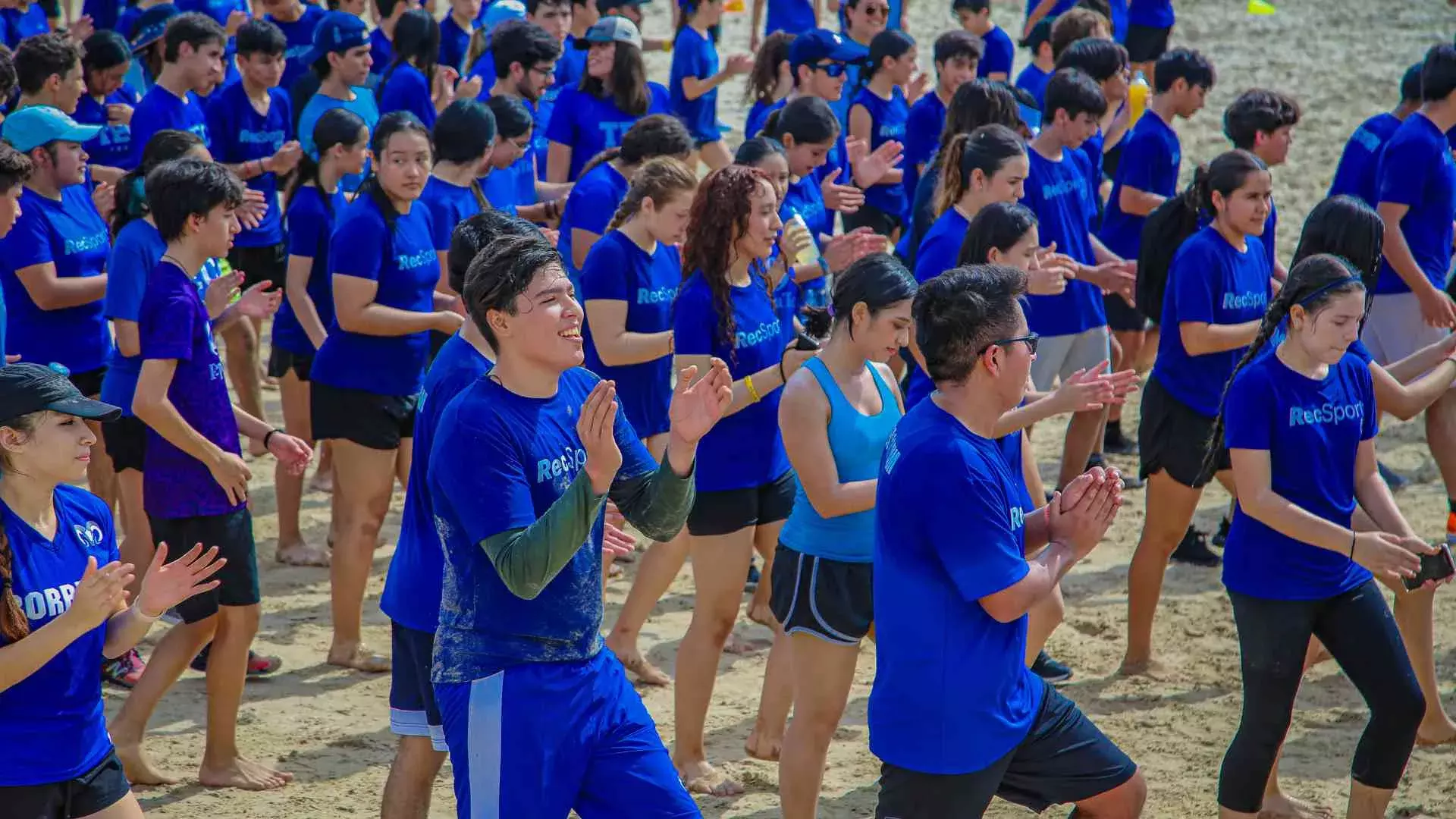 alumnos bailando en grupo en la orilla de la playa