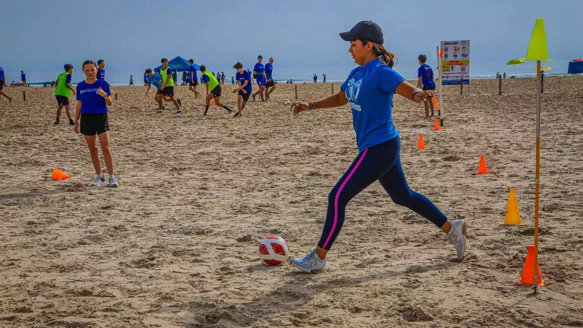 Alumna pateando balón de fútbol en la playa