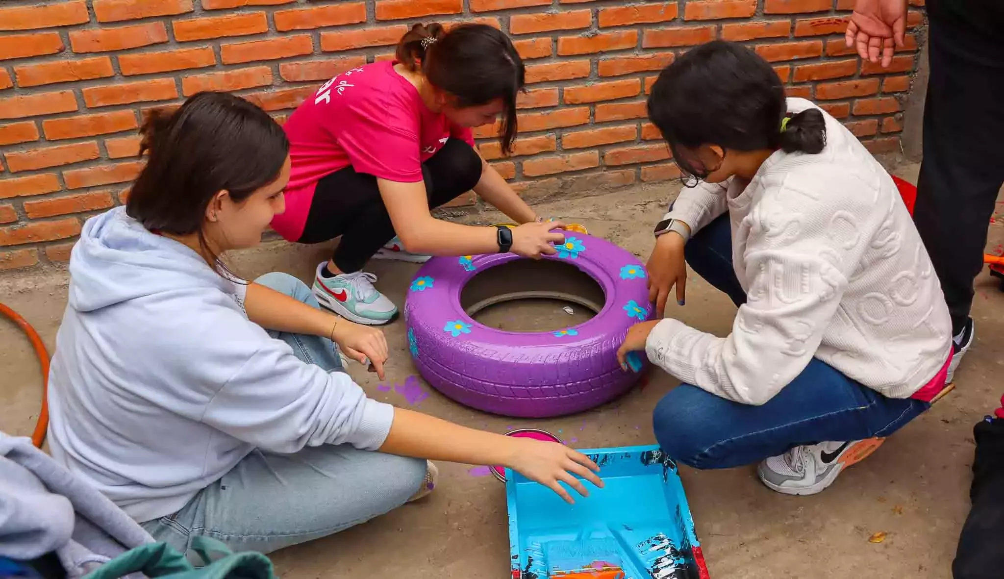 Alumnos decorando llantas para el patio del colegio en Voluntariado Tec