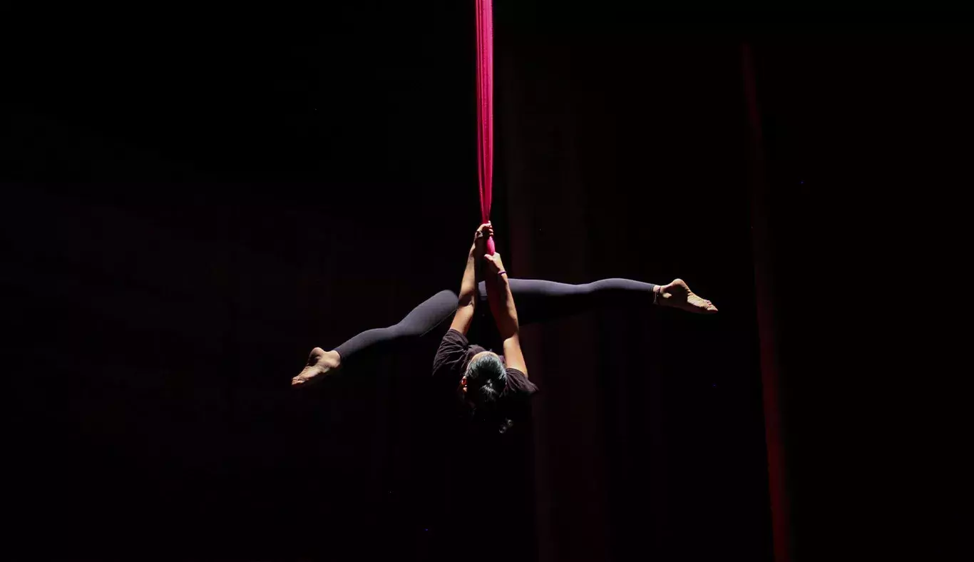 Chica de cabeza colgada de telas en número de danza aérea. 