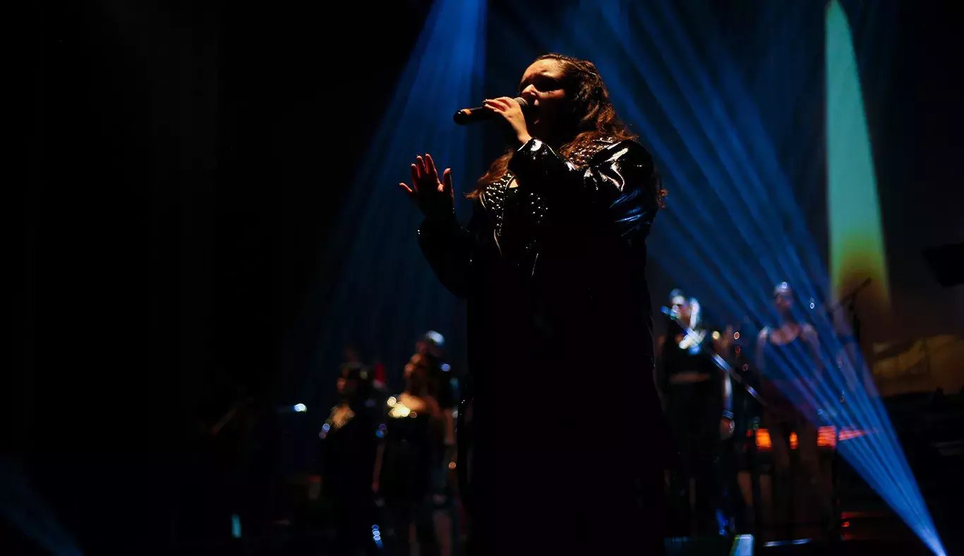 Cantante vestida de negro con luz iluminando su cara. 