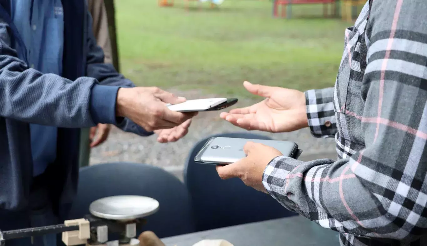 Hombre entrega celulares para campaña de reciclaje, en campus Monterre