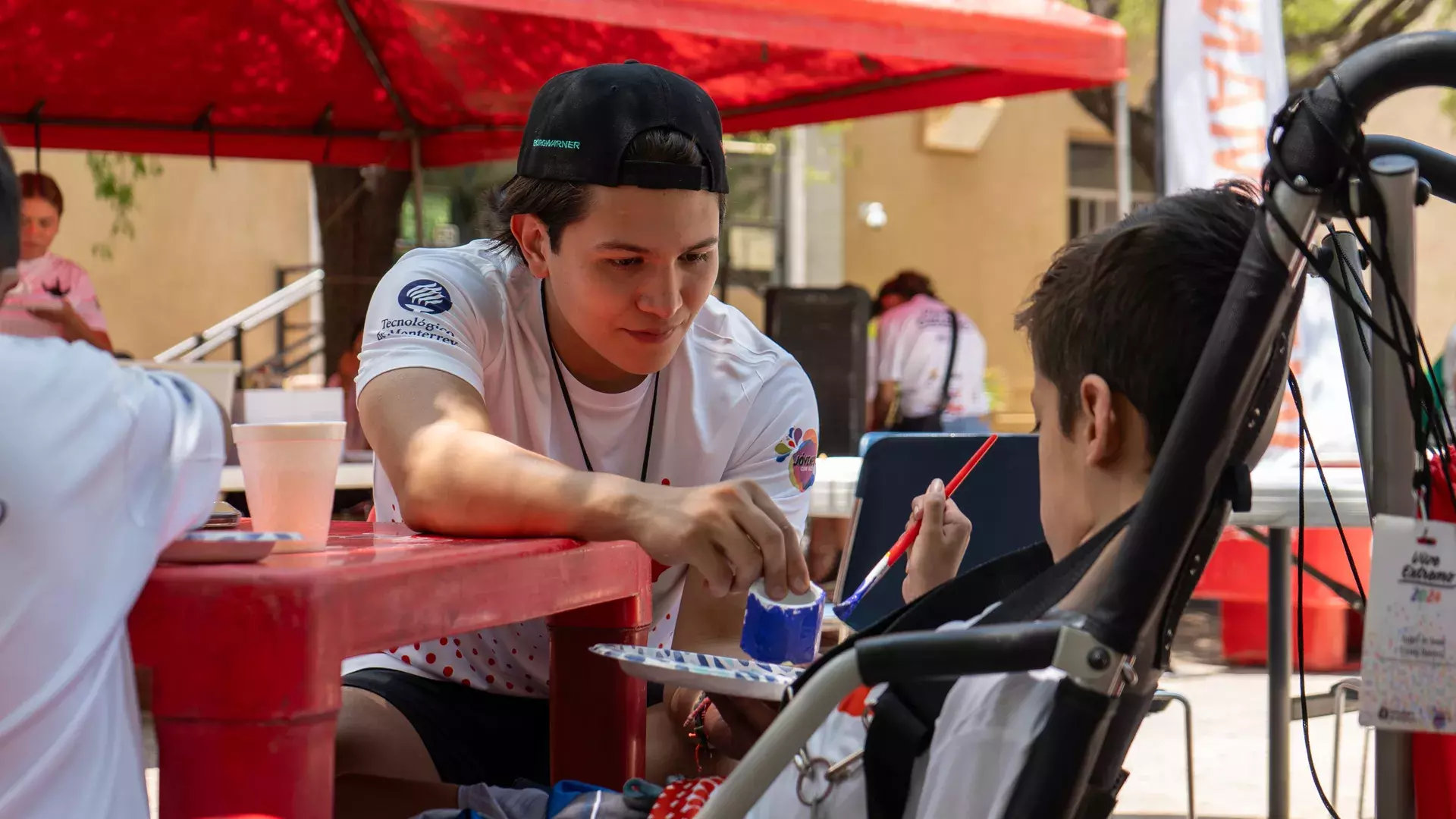 Estudiante ayudando a participante en su manualidad en Vive Extremo Camp