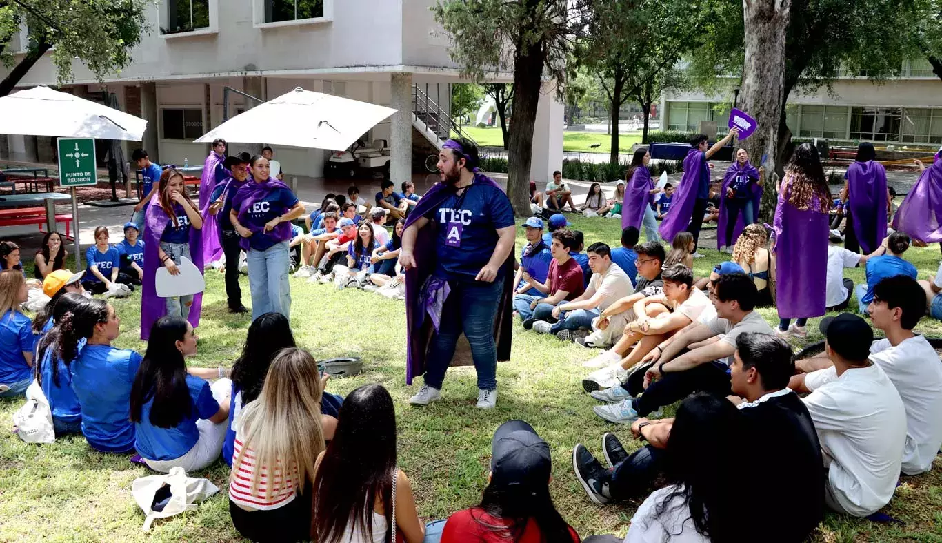 Alumnos sentados en círculo escuchando indicación de un estudiante.