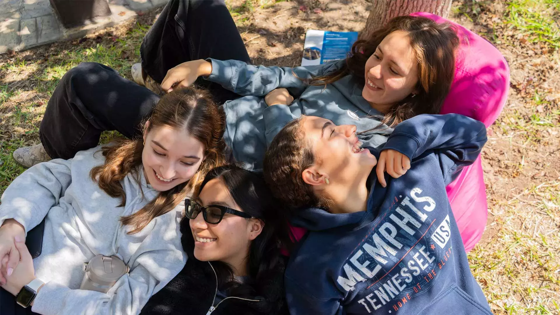 Alumnas acostadas en jardín sonriendo