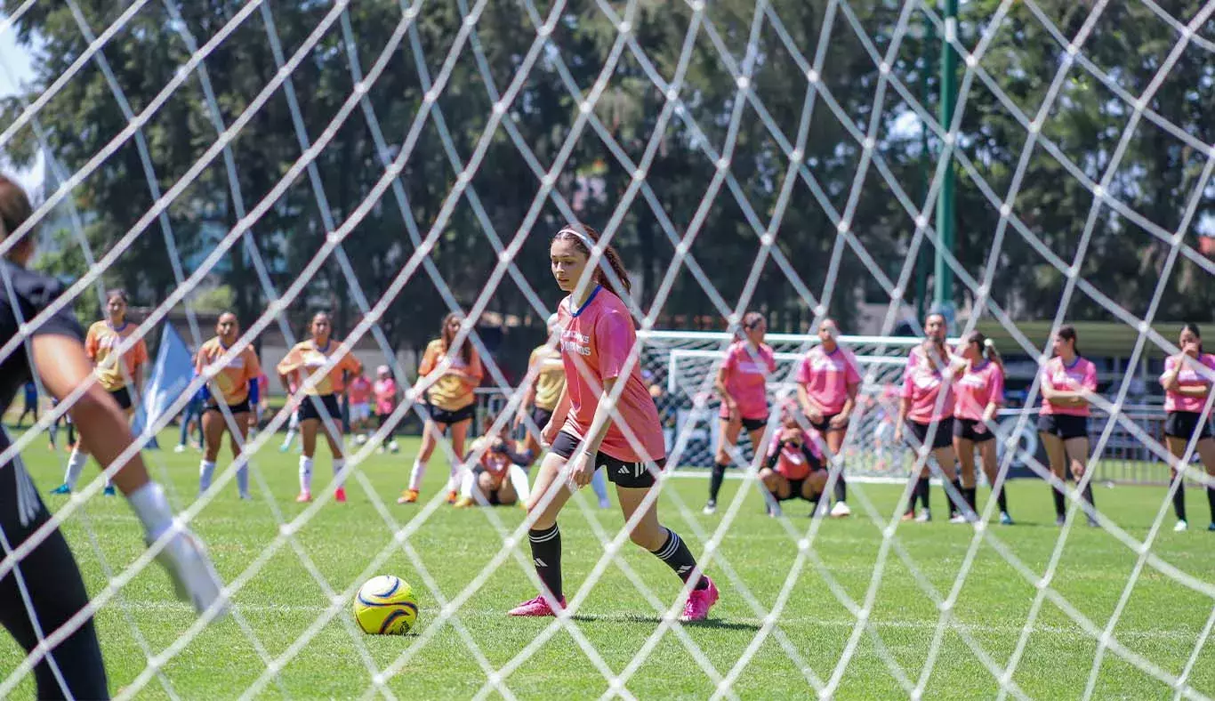 Vista de una jugadora de futbol a través de la red de la portería. 