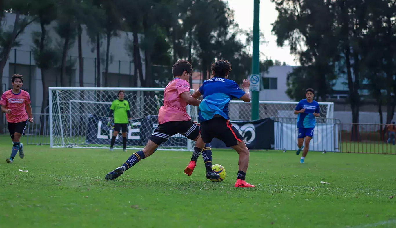 Jadores de fútbol compiten por el balón de espaldas a la cámara. 