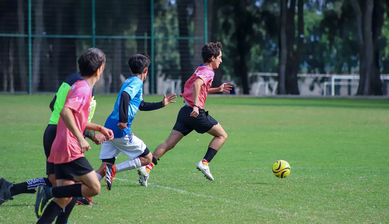 Jugadores de fútbol soccer corriendo tras el balón. 