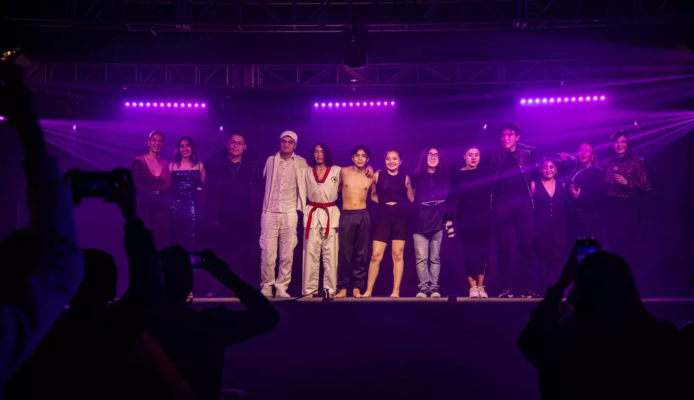 Estudiantes de las comunidades de profesional REVO y KREI que participaron en Tec's Got Talent, posando bajo luces moradas.