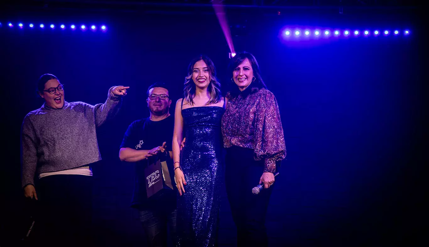 Valentina, ganadora del primer lugar en Tec's Got Talent, posando junto a la mentora de la comunidad REVO y los jueces, rodeada de luces azules.