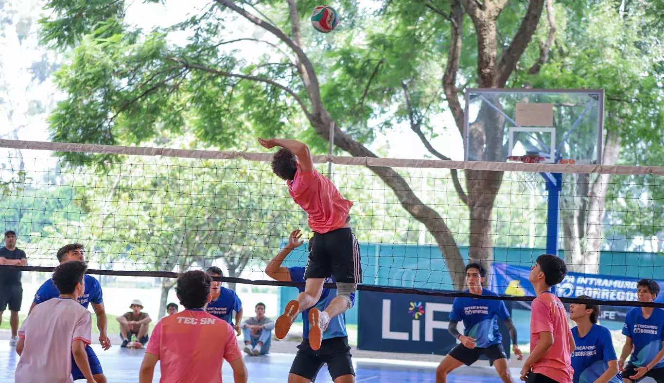 Jugador de voleibol saltando para rematar balon. 