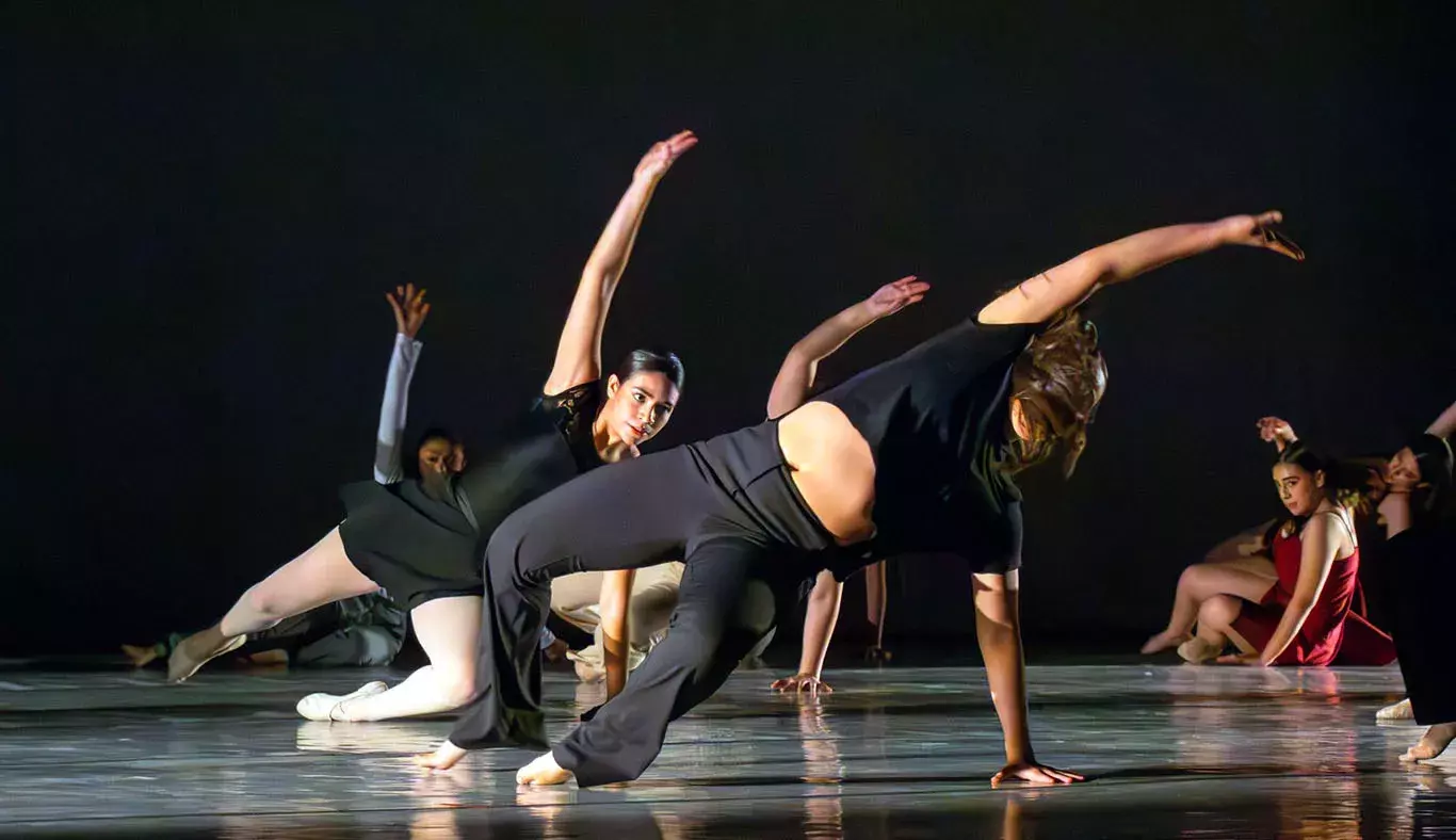 Bailarinas del Tec de Monterrey campus Laguna se presentan sobre fondo negro y realizan figuras en el suelo del Teatro Isauro Martínez