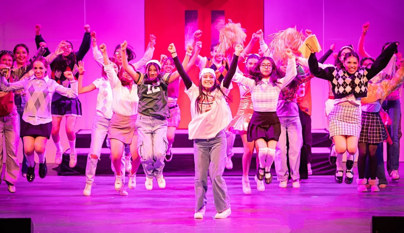 Estudiantes del Tec de Monterrey realizan una coreografía grupal durante un número musical de High School Musical: On Stage, con vestuarios escolares y expresión escénica activa.