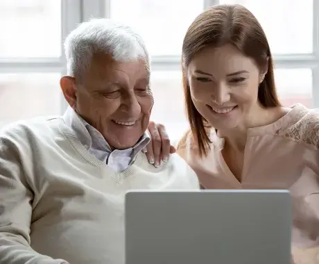 Adulto mayor y mujer joven usando una laptop