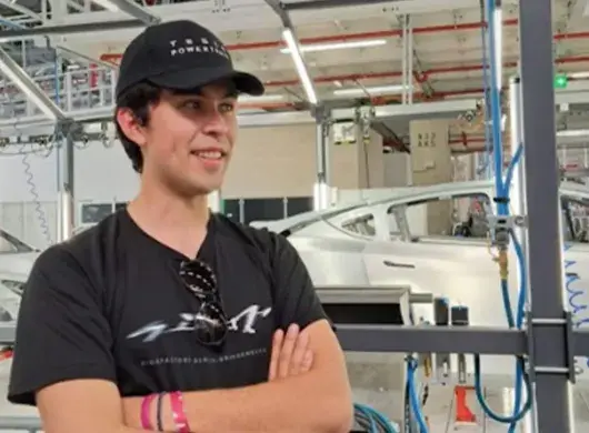 Estudiante posando para una foto en una planta automotriz