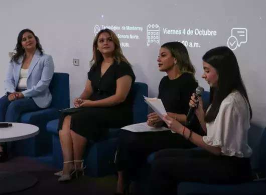 5 mujeres sentadas en sillones azules platicando