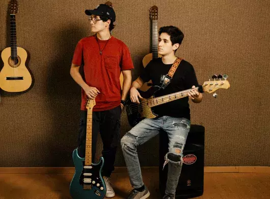 Hermanos posan con guitarra y bajo en espacio musical del Tec de Monterrey