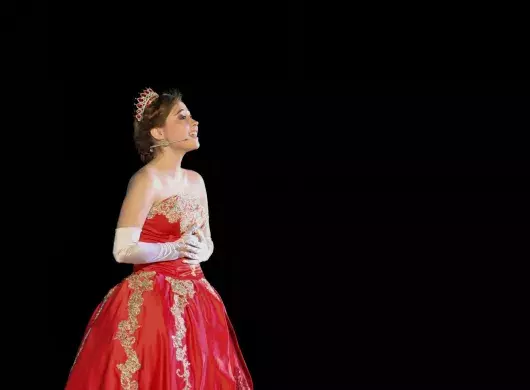 Anastasia cantando, usa un vestido rojo y una corona