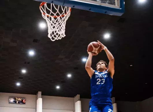 Jugador de Borregos Laguna salta y lanza balón de básquetbol para encestar