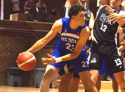 Jugador de básquetbol con uniforme de Borregos Laguna disputa el juego contra atletas con uniforme negro