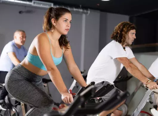 Gente en gimnasio en bicicletas estáticas