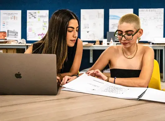 Estudiantes de arquitectura comparten mesa de trabajo con laptop y planos en el Tec de Monterrey campus Laguna