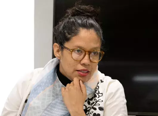 Profesora con lentes, ropa blanca y el cabello sujetado