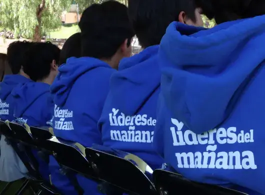 Estudiantes beneficiarios de becas de espaldas en evento