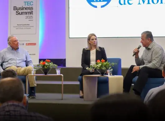 Dos hombres y una mujer platicando en escenario como parte de un foro.
