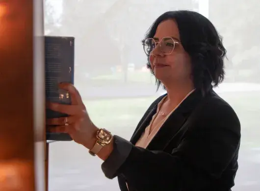 Directora de Mentoría de PrepaTec Laguna con vestimenta profesional toma libro de estante