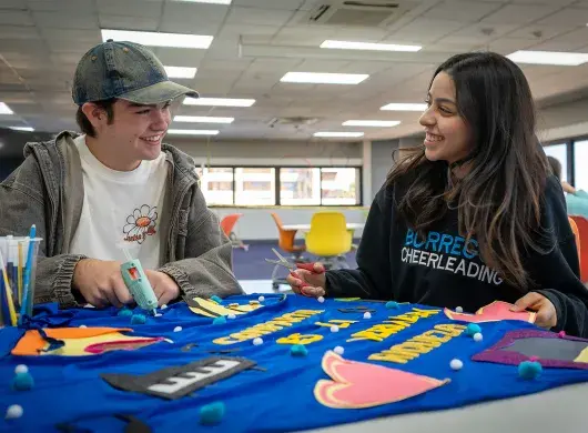 Dos alumnos sonriendo y mirándose.