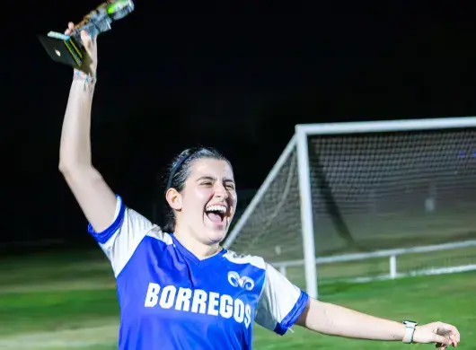 Jugadora de Borregos Laguna con uniforme azul y blanco festeja con el trofeo de primer lugar el campeonato femenil de fútbol soccer