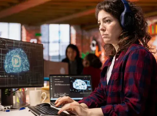 estudiante universitaria con audifonos viendo varias pantallas 