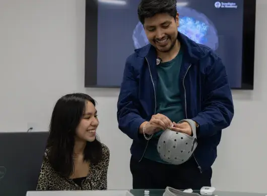 Un profesor del Tec CCM ajustando un casquete de electroencefalograma (EEG) en la cabeza de un estudiante dentro del MKT Research Lab.