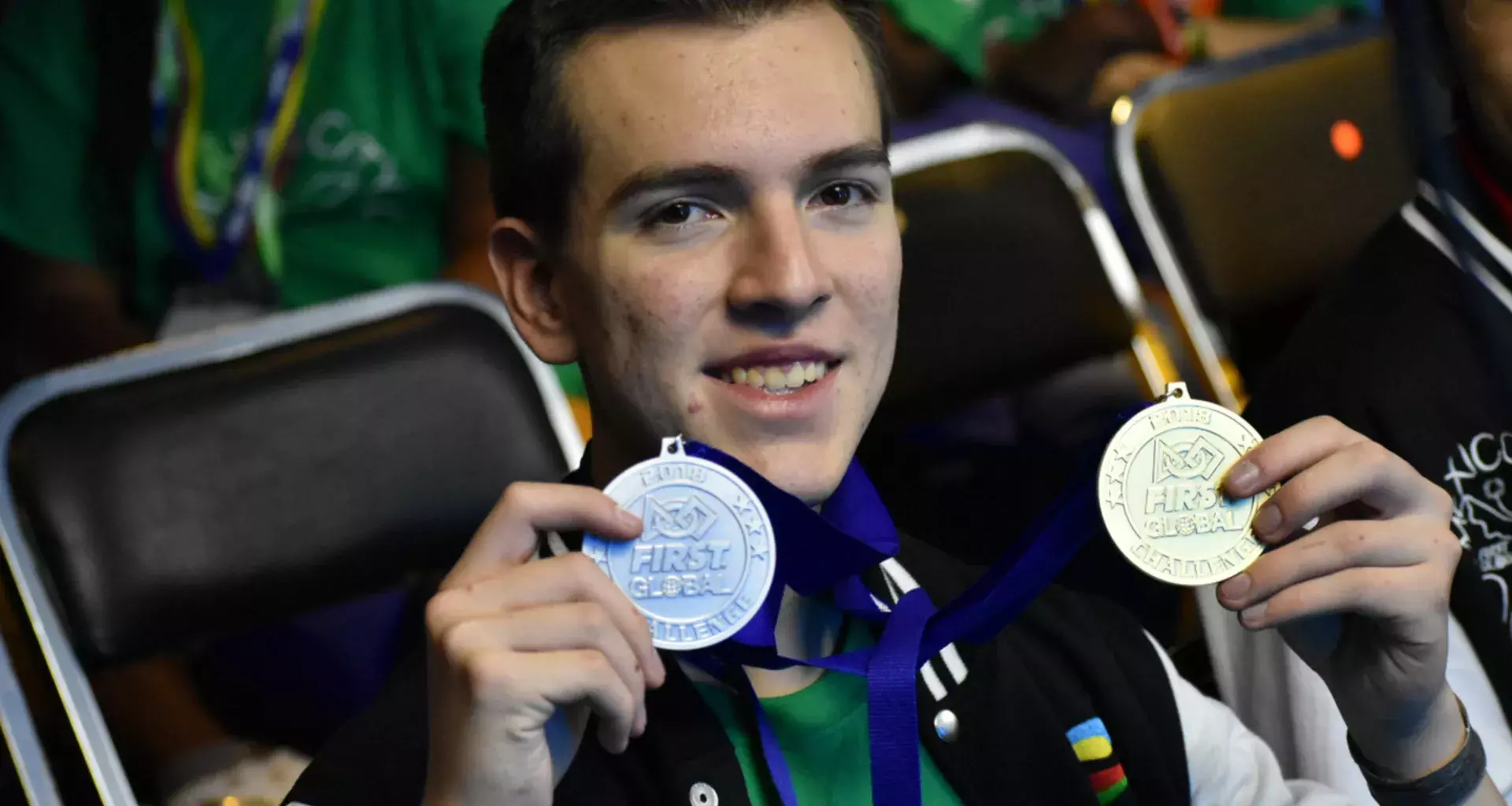 Joven sostiene medalla de oro y bronce mientras sonríe a la cámara