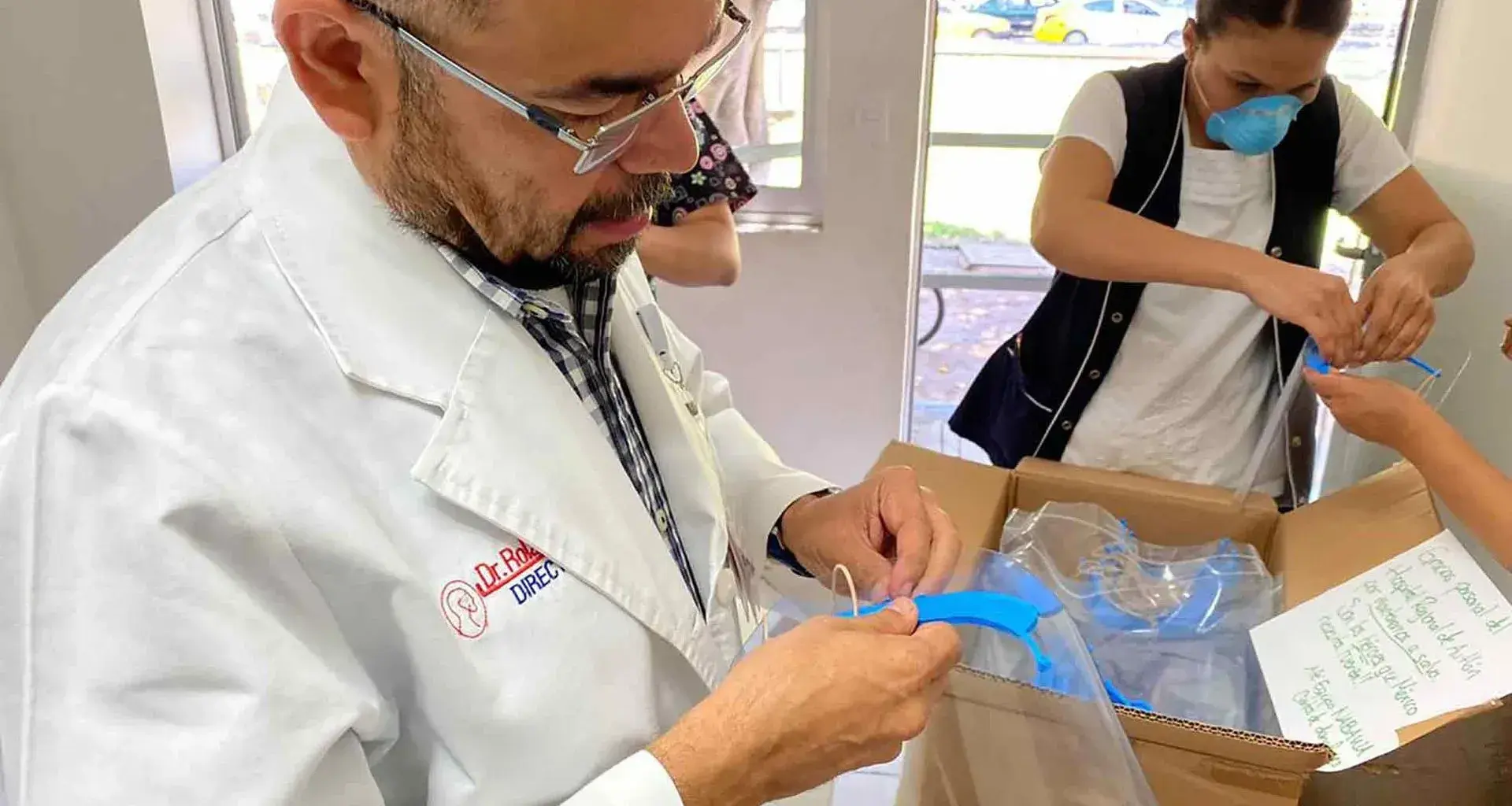 doctor abre paquete de proyecto nabawa de egresados del Tec con caretas médicas para combatir covid19.