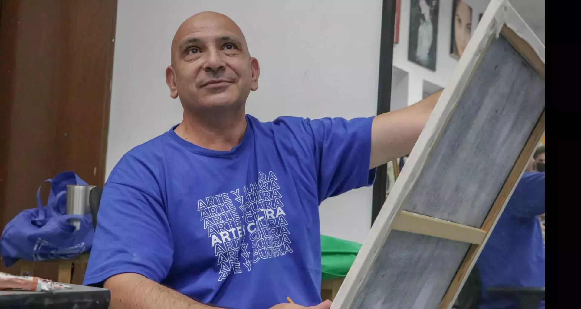 Profesor de artes plásticas pintando un cuadro con ligera sonrisa volteando hacia arriba.