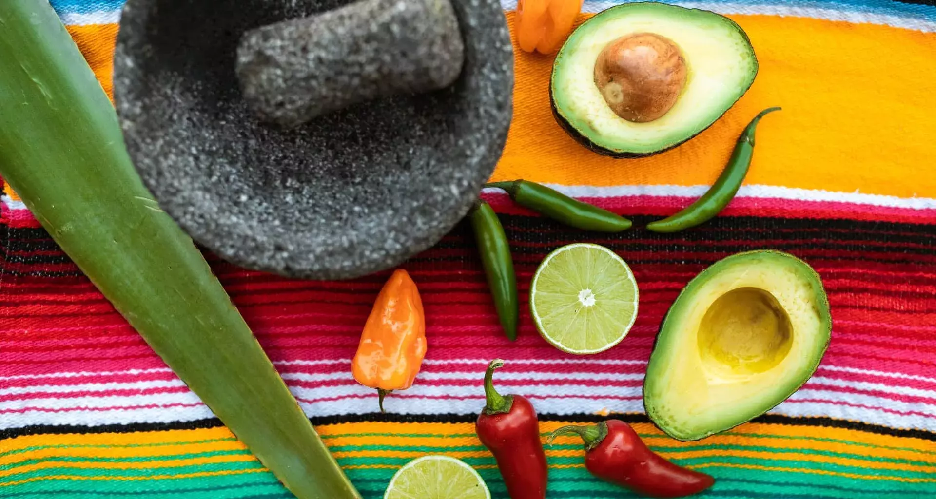 Imagen de manta con molcajete, aguacate, limón y chiles.