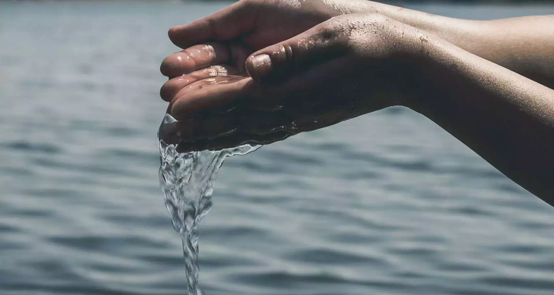 Manos agarrando agua y dejándola caer. 