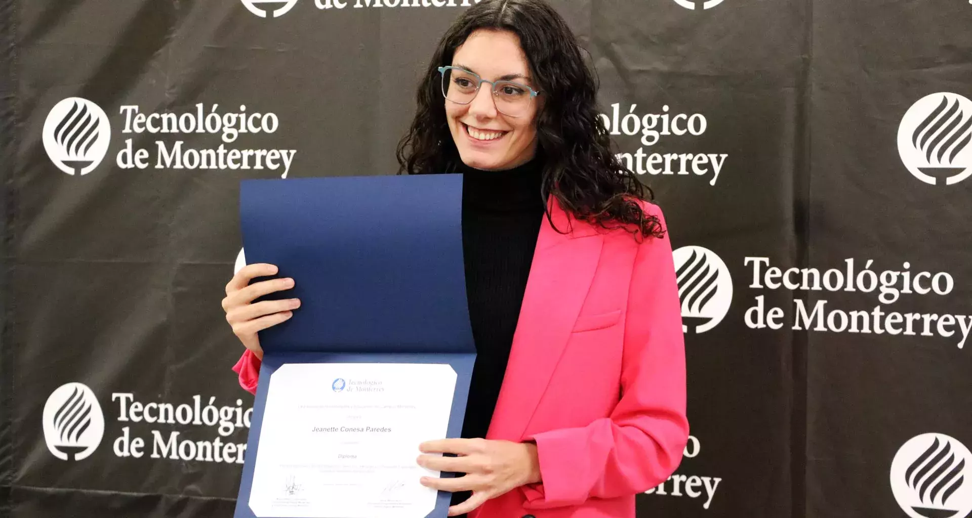 La profesora Jeanette Conesa posando junto a su reconocimiento.