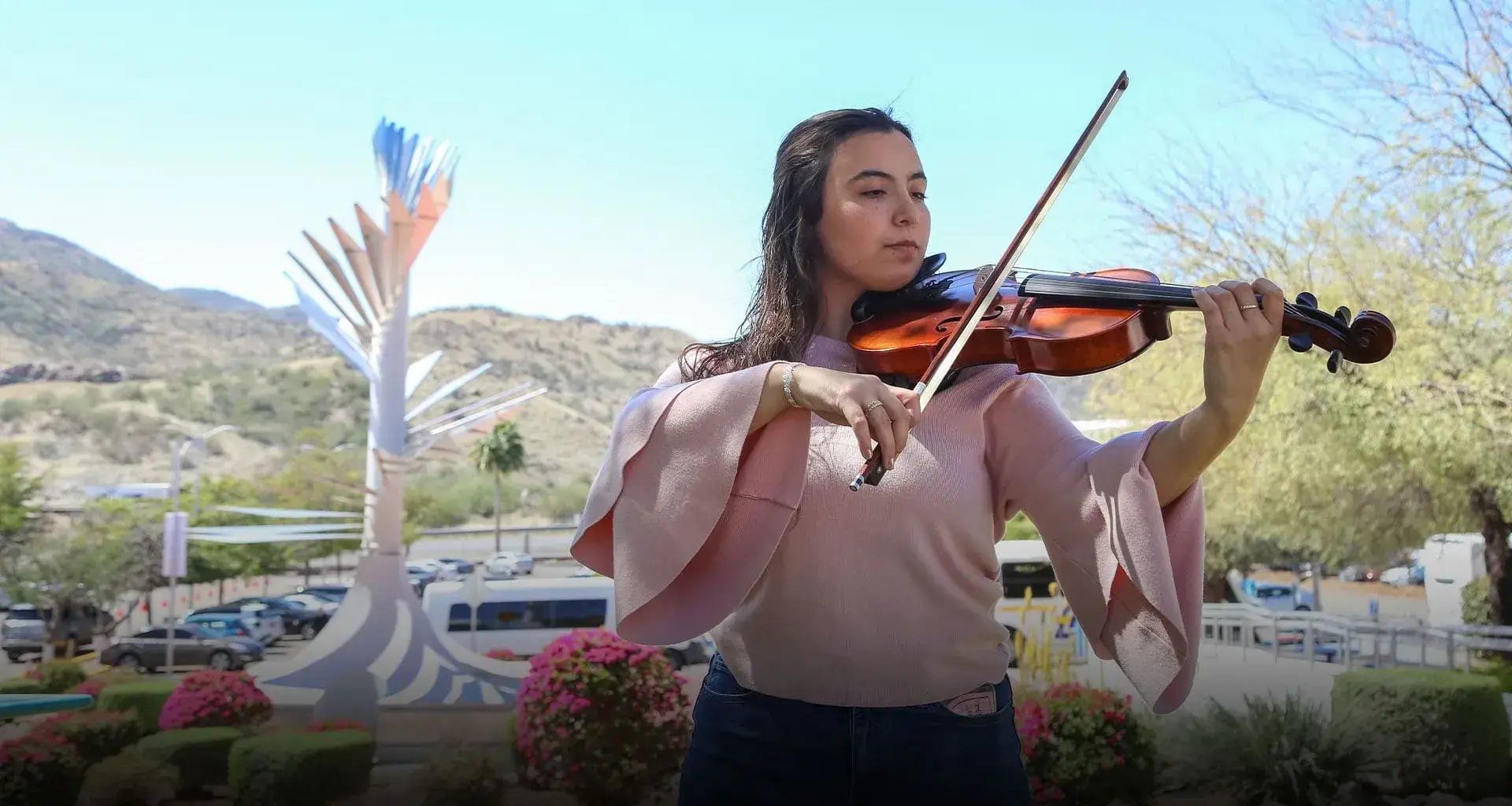Mariana Páez tocando la viola frente a una vista de la Cápsula del Tiempo del campus Sonora Norte
