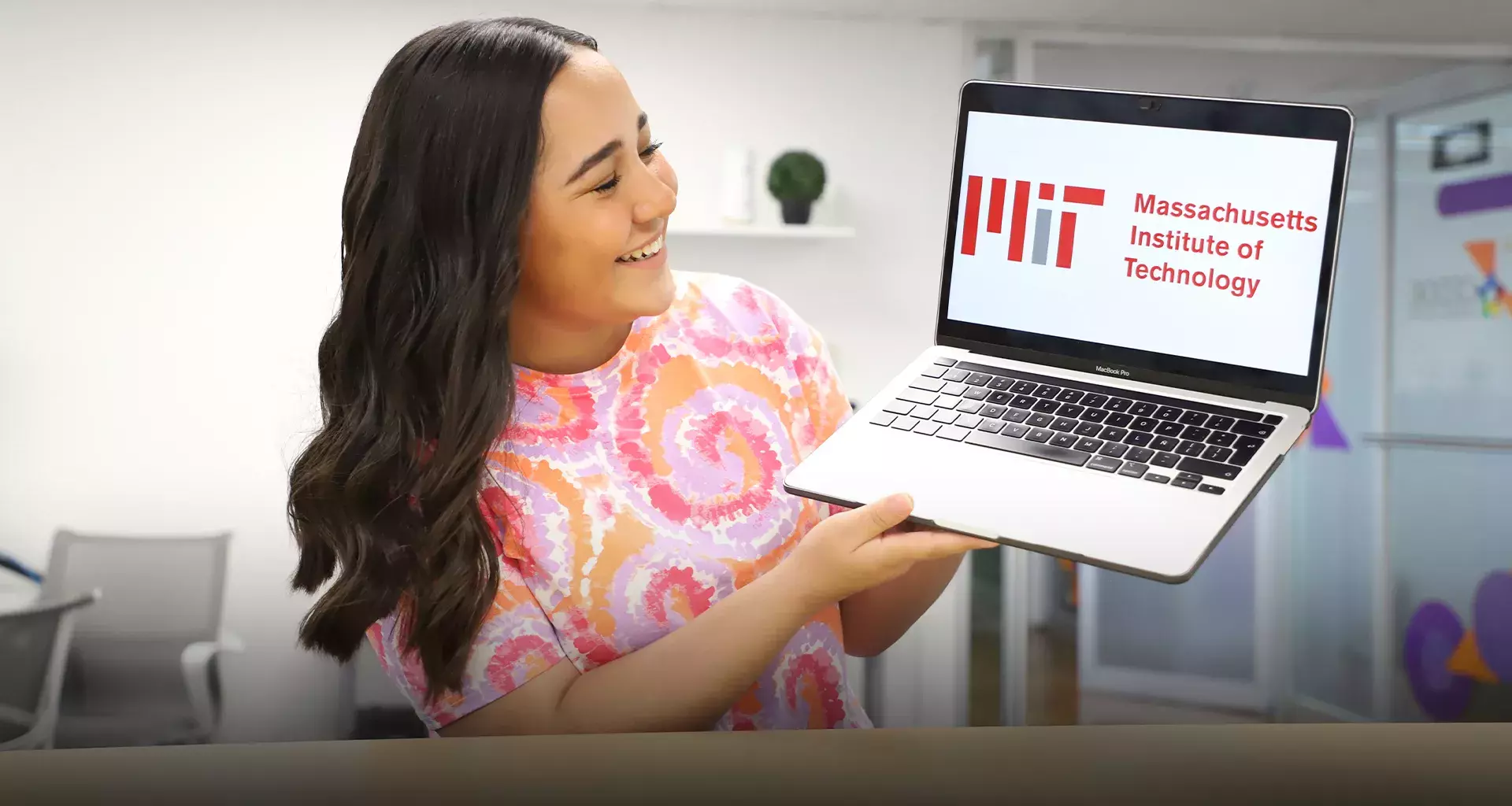 María Guadalupe Córdova sostiene en sus manos una computadora que muestra en pantalla el logo del MIT.