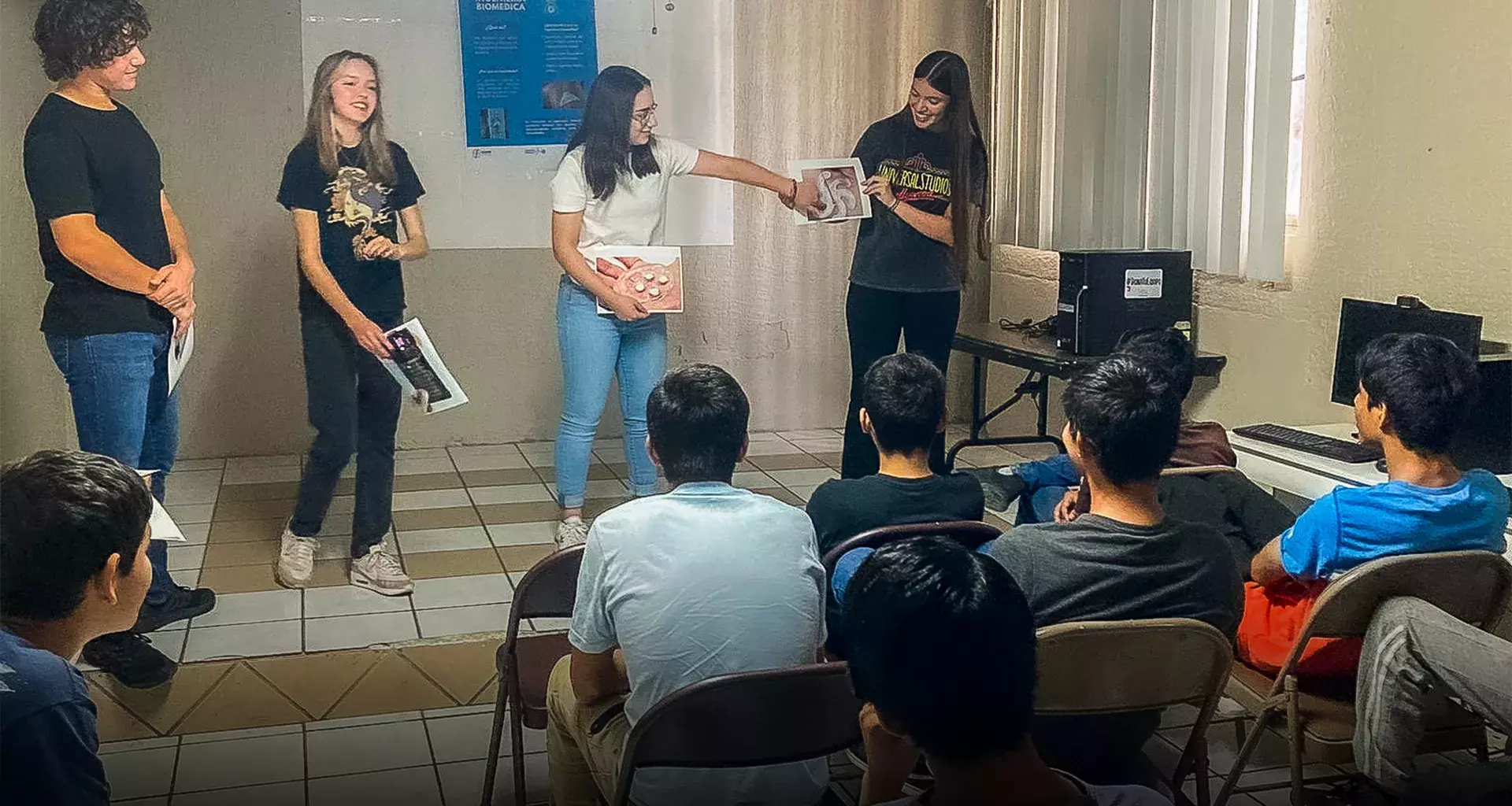 Estudiantes enseñando ciencia frente a un grupo. 