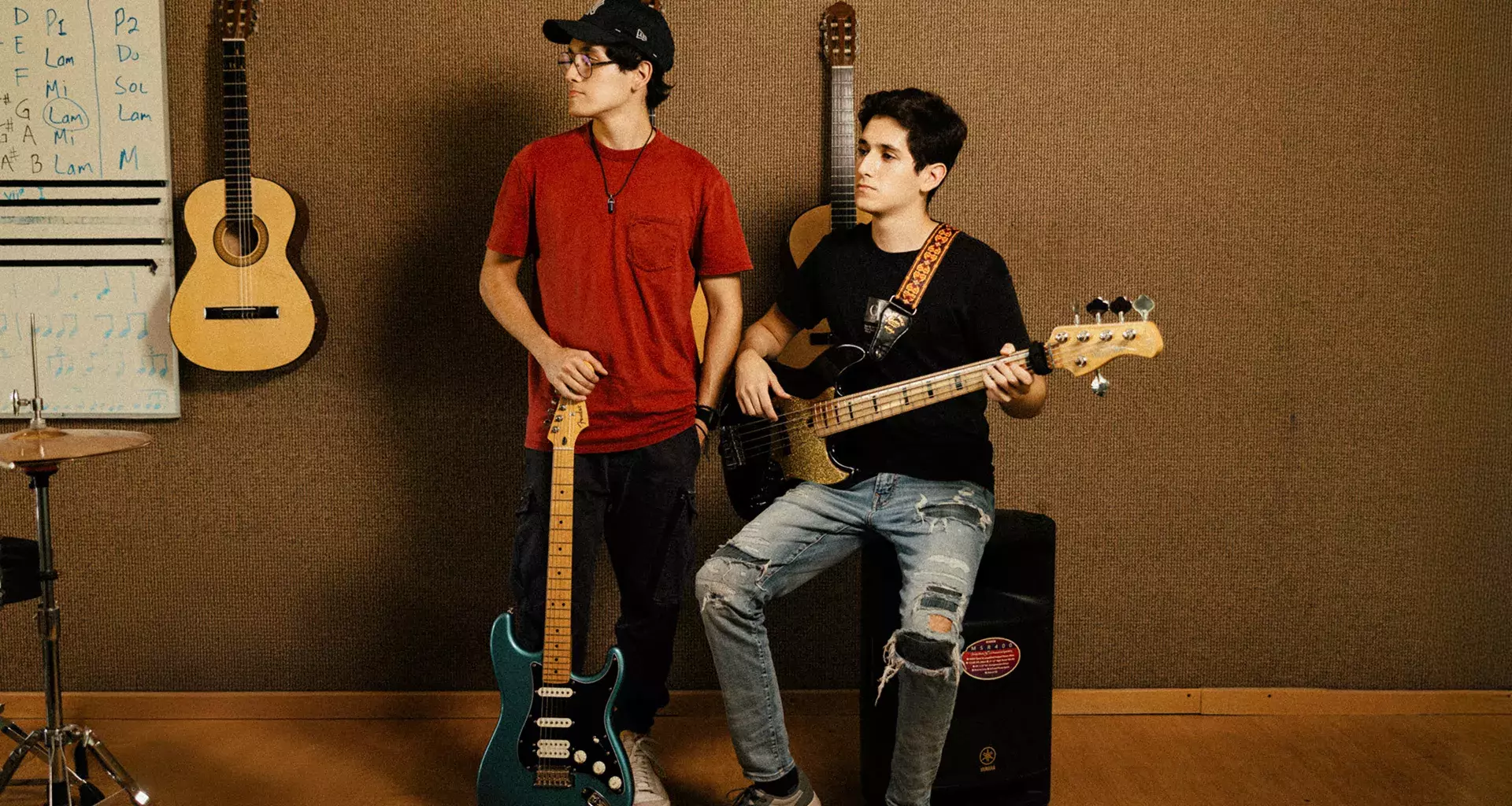 Hermanos posan con guitarra y bajo en espacio musical del Tec de Monterrey